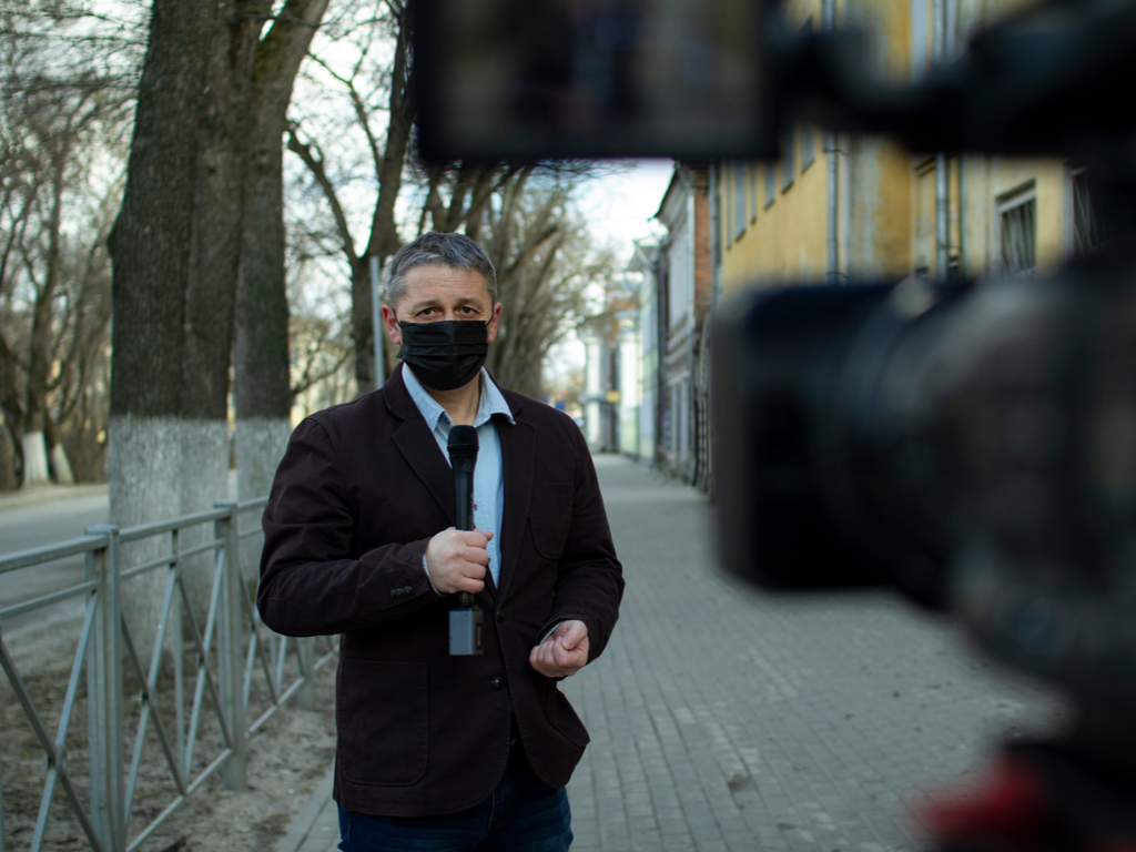 Repórter usando máscara em cidade vazia